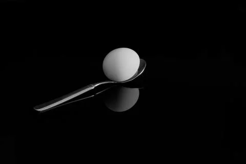 An egg on a spoon. With reflection on a black background Stock Photos