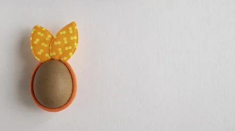 Egg with spots rabbit ears on white paper background. Copy space. Flat lay. Stock Photos