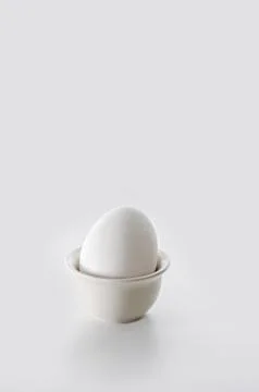 The egg in the stand on a white background. High key, selective focus Фото