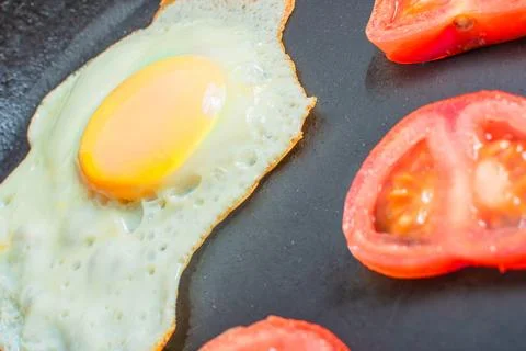 Egg, sunny side up, with fresh tomatoes in a frying pan Stock Photos