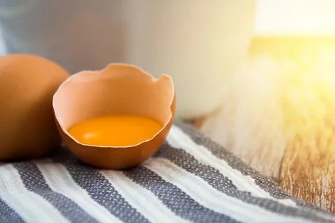 Egg, yolk in an eggshell on a wooden background. Preparing breakfast. Stock Photos