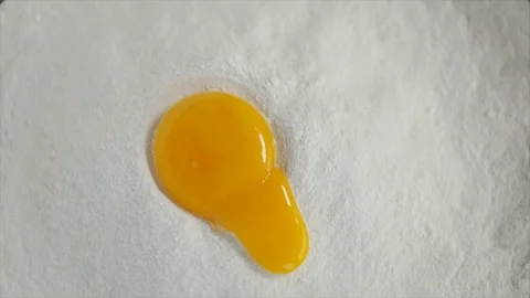 Egg Yolk Falling into Flour and Running Out Closeup Stock Footage 99162735