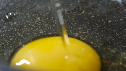 Egg yolk falling on hot pan, illustrating nutritious breakfast preparation Stock Footage 312846129