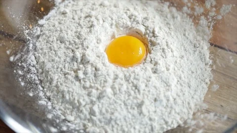 Egg Yolk Falling into Pile of Flour on Wooden Table Stock Footage 99162727