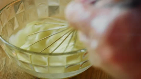Egg yolks whisked vigorously inside a patterned glass bowl, 4K Stock Footage 341119074