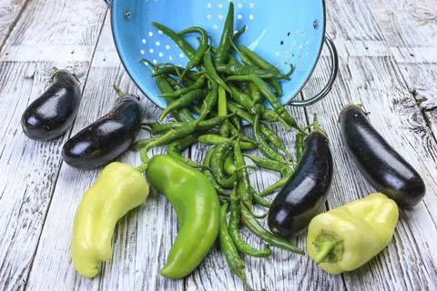 Eggplant and various peppers on table. Stock Photos