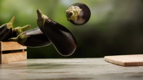 Eggplants falling in slow motion over table Stock Footage 156787686