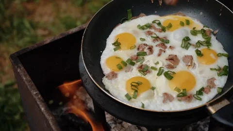 Eggs and bacon in the frying pan with organic greens, green grass on the blurred Video stock 205848464