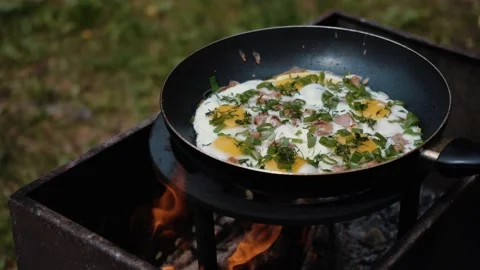 Eggs and bacon in the frying pan with organic greens, green grass on the blurred Video stock 205848641