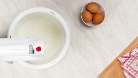 Eggs and sugar are placed mixer works. Whipping dough for pancakes. 库存影片 148928675