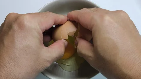 The eggs are cracked open, their yolks falling gently into the bowl. Stock Footage 318010000