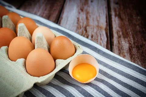 Eggs background. Eggs in a cardboard box on a wooden background. Yolk in an Stock Photos