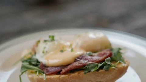 Eggs Benedict with bread and tomato on a plate with becon morning sandwich Stock Footage