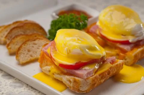 Eggs benedict on bread with tomato and ham Stock Photos