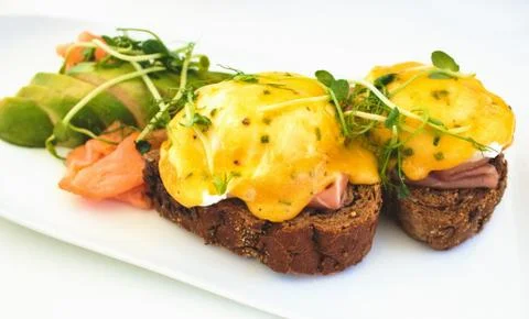 Eggs Benedict on brown bread toast with smoked salmon and sliced avocado Stock Photos