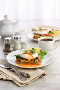 Eggs Benedict with guacamole on cereal bread Stock Photos
