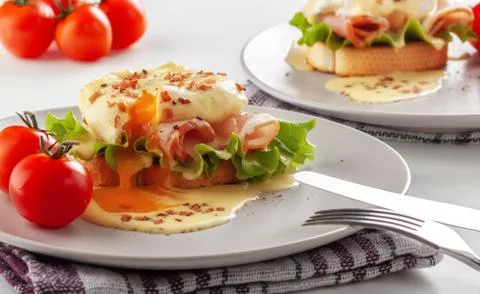 Eggs Benedict on toasted muffins with ham and sauce Stock Photos