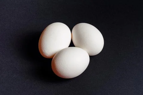 Eggs on a black background, three eggs in a row, shadow on the background of  Fotos de archivo