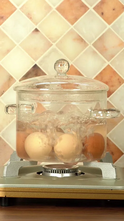 Eggs boiling in a glass pot over a gas stove 스톡 동영상 270458571