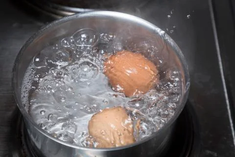 Eggs in boiling water Stock Photos