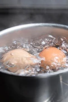 Eggs in boiling water Stock Photos