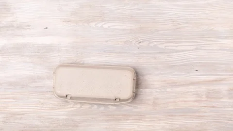 Eggs in box move and disappear on wooden background Video stock 127103341