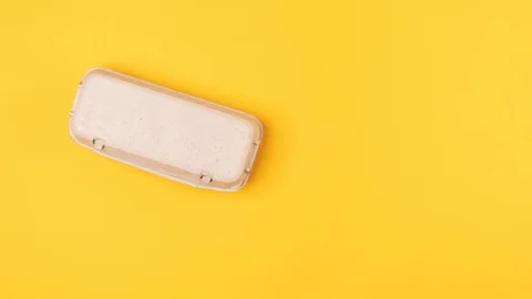 Eggs in box tray move horizontally on yellow background Stock Footage 127103222