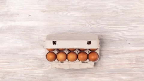 Eggs in cardboard tray moves from the bottom on wooden background Stock Footage 141017347