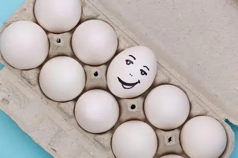 Eggs in a carton with one egg having a smiling face drawing Stock Photos