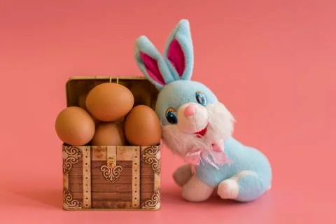 Eggs in a chest and easter bunny. Easter concept on pink background Stock Photos