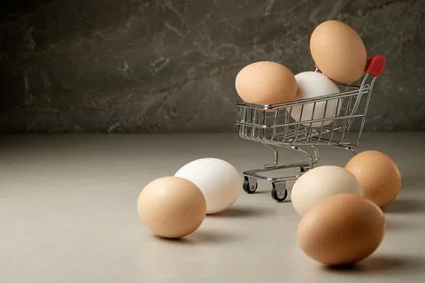 Eggs on display in a tiny shopping cart against a textured background Stock Photos
