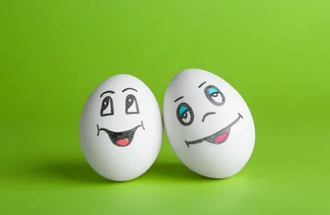 Eggs with drawn happy faces on green background Stock Photos