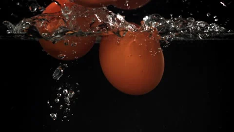 Eggs falling under water on a black background. Filmed on a high-speed camera at Stock Footage 322816626