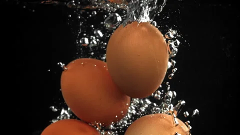 Eggs falling under water on a black background. Filmed on a high-speed camera at Stock Footage 322829920
