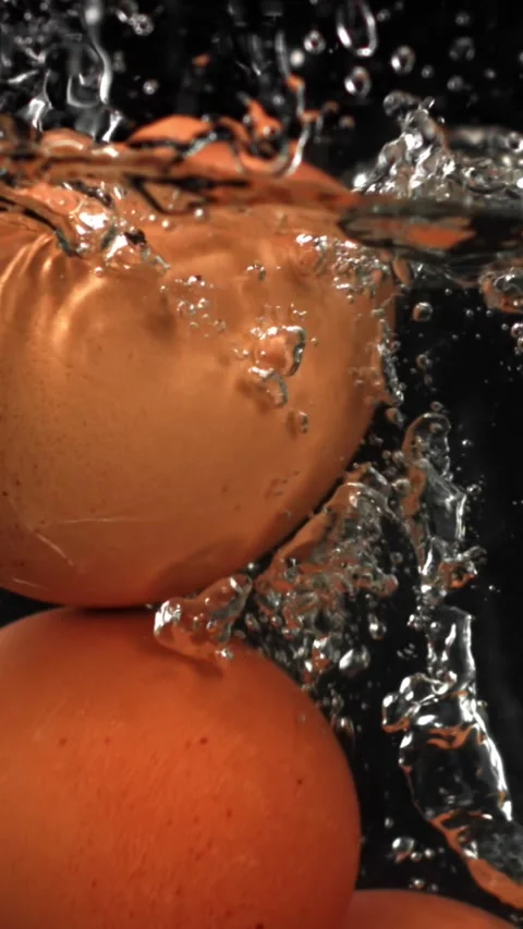 Eggs falling under water on a black background. Filmed on a high-speed camera at Video stock 335367414
