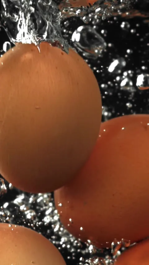 Eggs falling under water on a black background. Filmed on a high-speed camera at Video stock 335371738