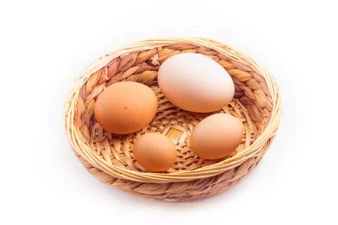 Eggs - four chicken eggs of different sizes in a small wicker basket Stock Photos