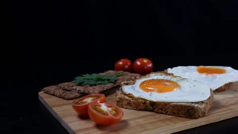 Eggs on a fresh grain bread, ripe cherry tomatoes and bread crips with parsley Stock Footage 99656345