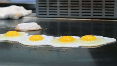 Eggs on the frying panel. Close-up shot of broken eggs being fried on frying Stock Footage 135223413