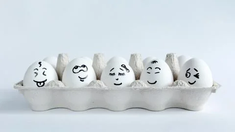 Eggs with funny faces in the package on a white background. Easter Concept . Stock Photos