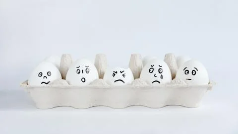 Eggs with funny faces in the package on a white background. Stock Photos