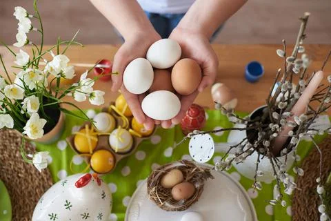 Eggs in the hands of a child on the background of Easter decorations Stock Photos