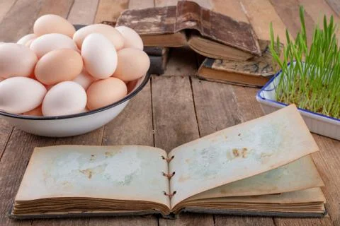 Eggs from hens and an old notebook on a wooden kitchen table. Fresh rye sprou 스톡 사진
