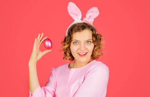 Eggs hunt. Happy Easter. Smiling Woman in bunny ears with pink egg. Rabbit gi Stock Photos