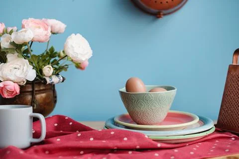 Eggs on a kitchen table next to flowers and a grater Stock Photos