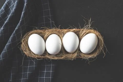 Eggs lined up in a row in a nest on black rustic background Stock Photos