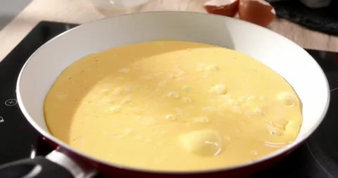 Eggs with milk are cooked into a frying pan. Making an omelet. Close up. Stock Footage 243772884