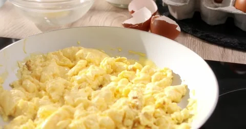 Eggs with milk are cooked into a frying pan. Making an omelet. Close up. Stock Footage 243772998