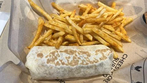 Eggs 'n Things breakfast burrito and seasoned french fries served on brande.. Stock Photos