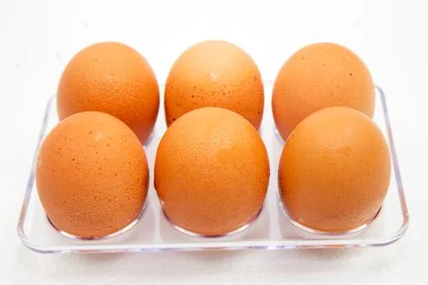 Eggs in plastic box on the white background. Droplets of water on eggs. Stock Photos
